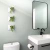Set of three 6 inch light gray vertical wall planters with frilly plant in white modern bathroom.