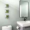 Set of three gray wall planters with house plants in a modern bathroom.
